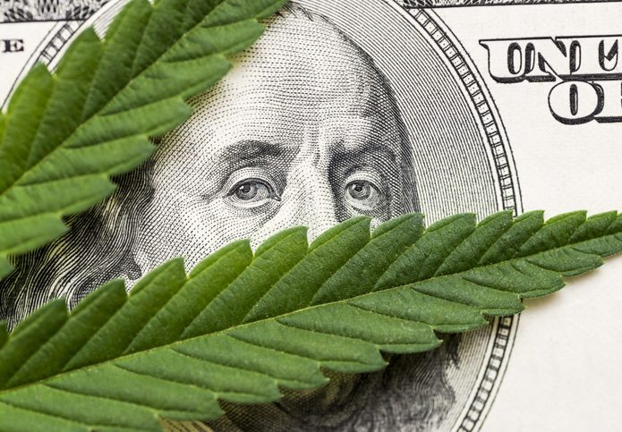 Cannabis leaves in front of Ben Frnaklin's face on a $100 bill.