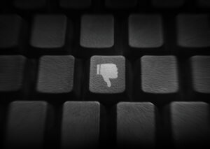 Keyboard in shadows, with a white "thumbs down" image on one of the keys.