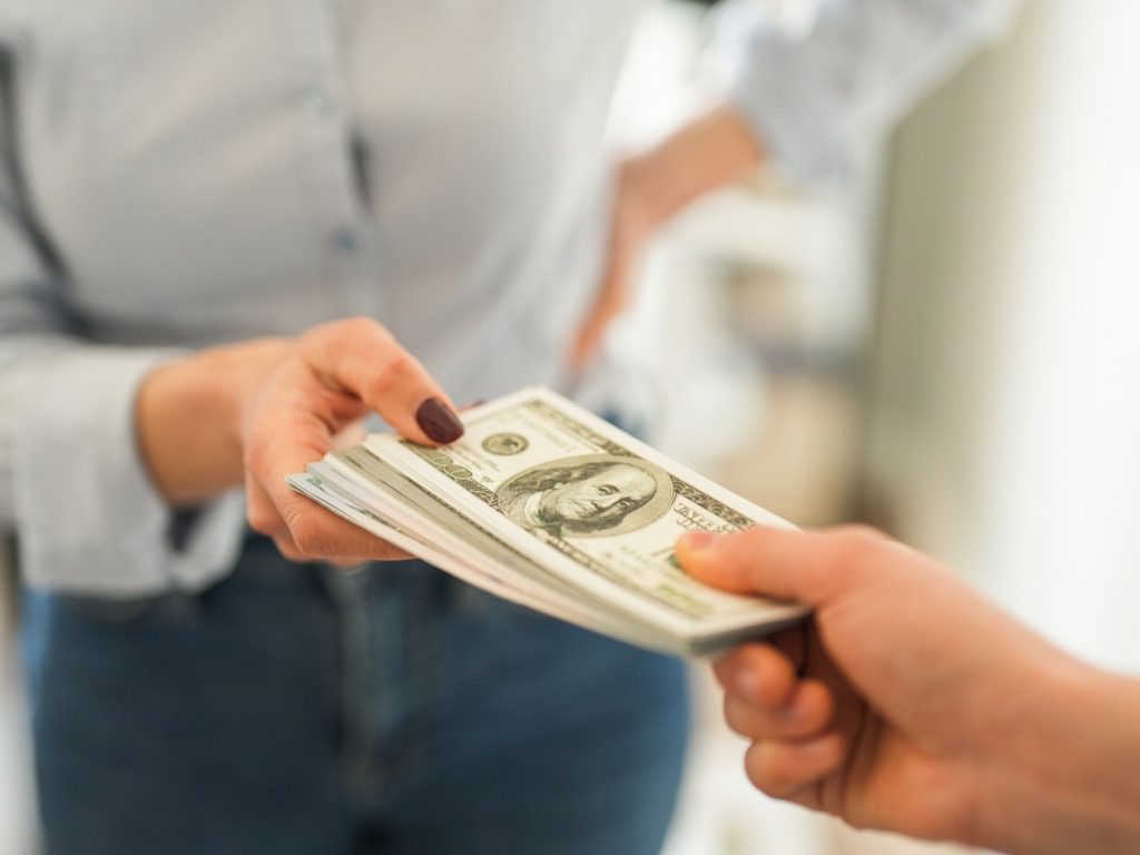 woman handing dollars to other person