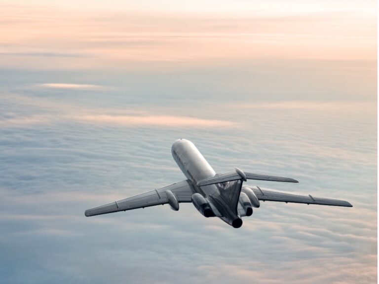 Plane flies above clouds into sunset