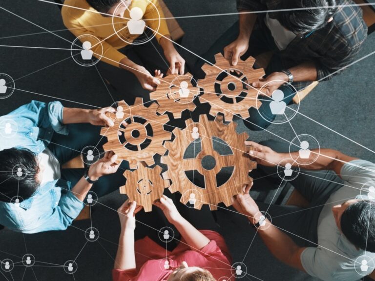 top-view-of-smart-business-people-joining-and-gathering-wooden-gear-symposium How Legal Ops Is Reshaping Cross-Functional Collaboration