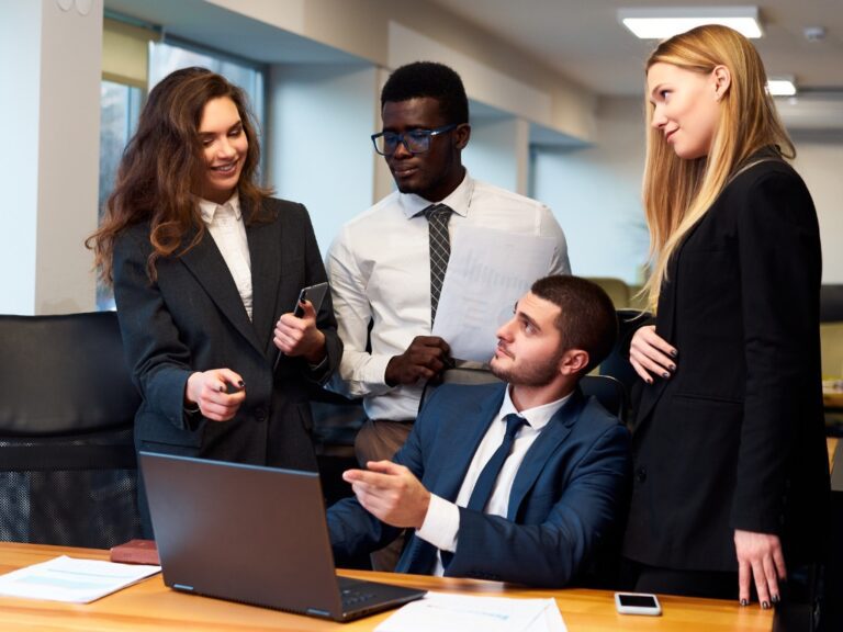 multiethnic-business-team-engages-in-lively-discussion-around-laptop-in-modern-office-setting How to Build Strategic Legal Operations for Business Agility in Uncertain Times